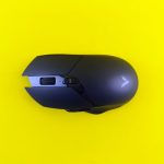 A sleek black gaming mouse rests on a bright yellow background, emphasizing contrast and design.