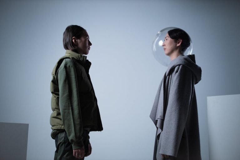 Artistic study of two persons facing each other, one wearing a transparent helmet, in a studio setting.
