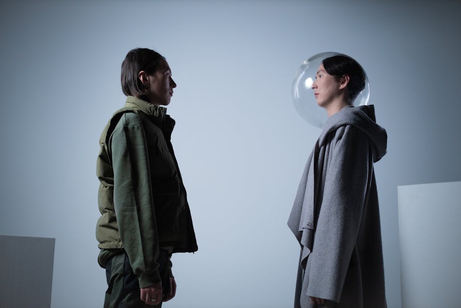 Artistic study of two persons facing each other, one wearing a transparent helmet, in a studio setting.