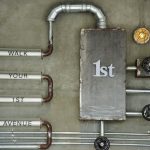 Industrial wall art featuring pipes and text on a concrete wall with a vintage style.