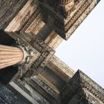 A close-up angular perspective of ornately carved ancient architectural columns with intricate detailing.