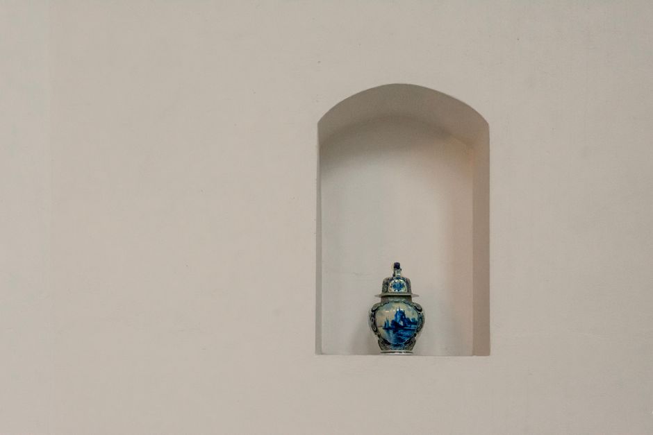 Elegant blue porcelain vase displayed on a minimalist white wall shelf with ample copy space.