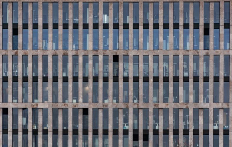 Front view of a modern office building's symmetrical facade with vertical lines.