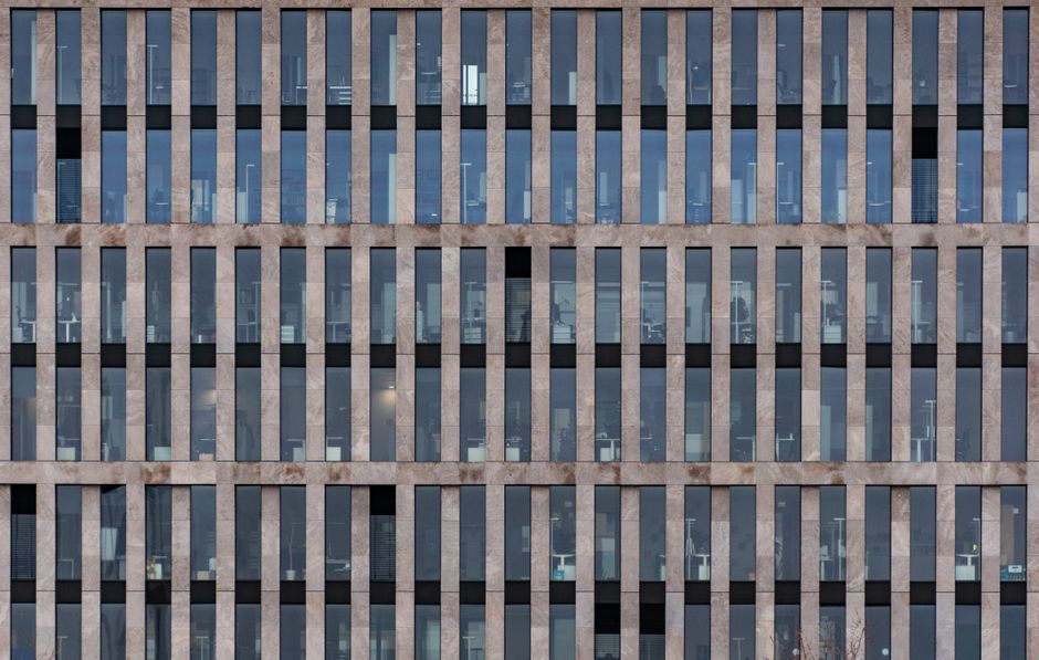 Front view of a modern office building's symmetrical facade with vertical lines.
