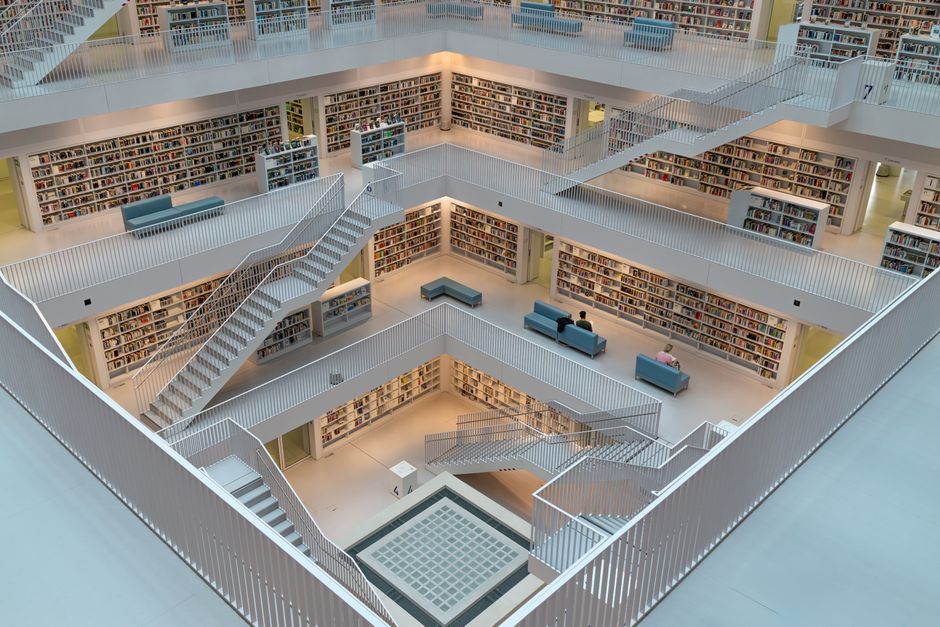 Explore the airy and geometric space of a modern library with intricate staircases and minimalist design.