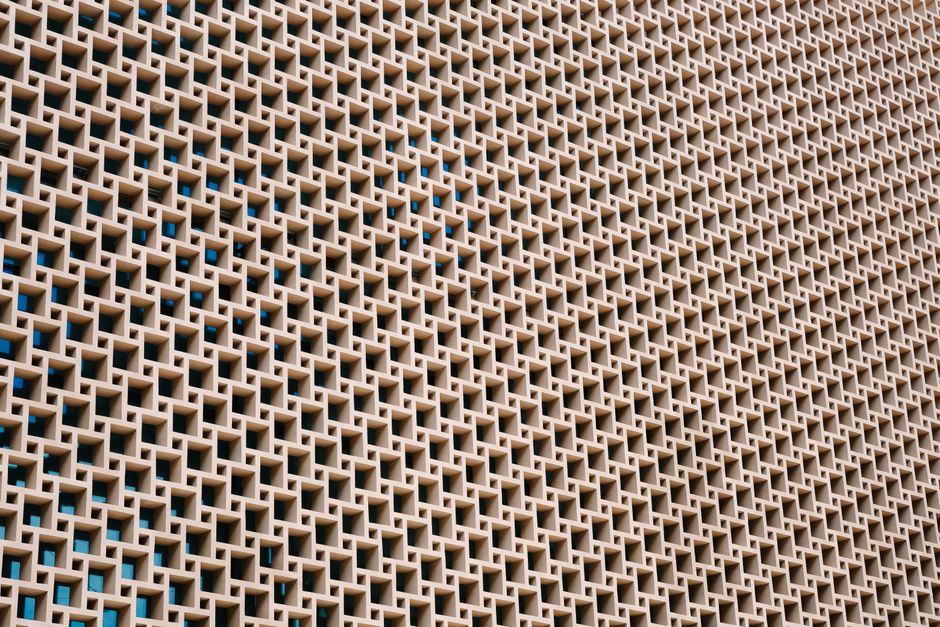 A detailed view of a geometric concrete wall with repetitive patterns and open spaces.