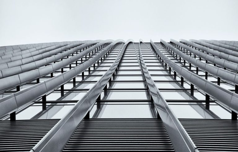 Low angle shot of a modern high-rise building showcasing its sleek architectural design in monochrome.