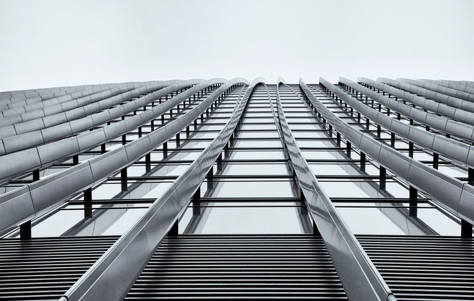 Low angle shot of a modern high-rise building showcasing its sleek architectural design in monochrome.