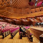 Spacious interior view of Sydney Opera House concert hall with seating and stage.