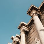 The Architecture of Influence: Why Hierarchy Drives Performance Majestic ancient columns stand tall under a clear blue sky, showcasing historic architectural beauty.