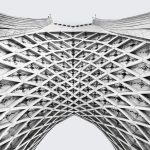 The Architecture of Perpetual Correction: Cybernetic Leadership Black and white abstract view of Azadi Tower's intricate geometric lattice in Tehran.