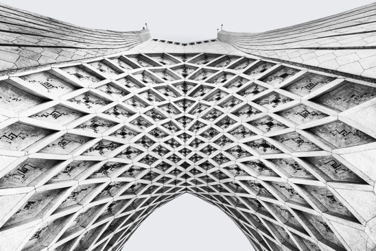 Black and white abstract view of Azadi Tower's intricate geometric lattice in Tehran.