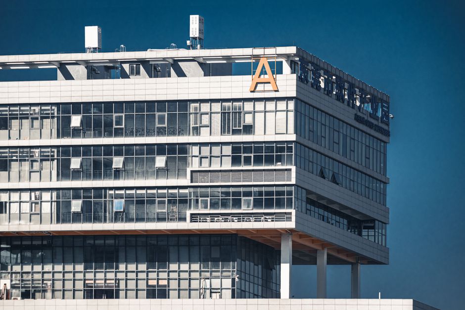 Close-up of a modern office building with glass facade under a clear blue sky.
