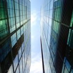 The Architecture of Sovereign Corporations: Autonomous Business Low angle view of glass skyscrapers reflecting blue sky in a contemporary urban setting.