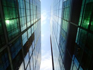 Low angle view of glass skyscrapers reflecting blue sky in a contemporary urban setting.