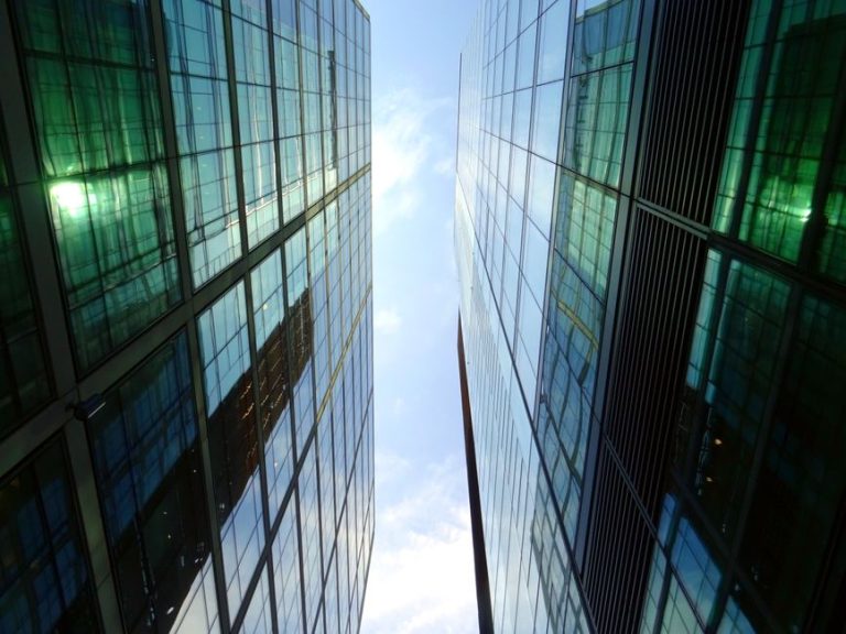 Low angle view of glass skyscrapers reflecting blue sky in a contemporary urban setting.