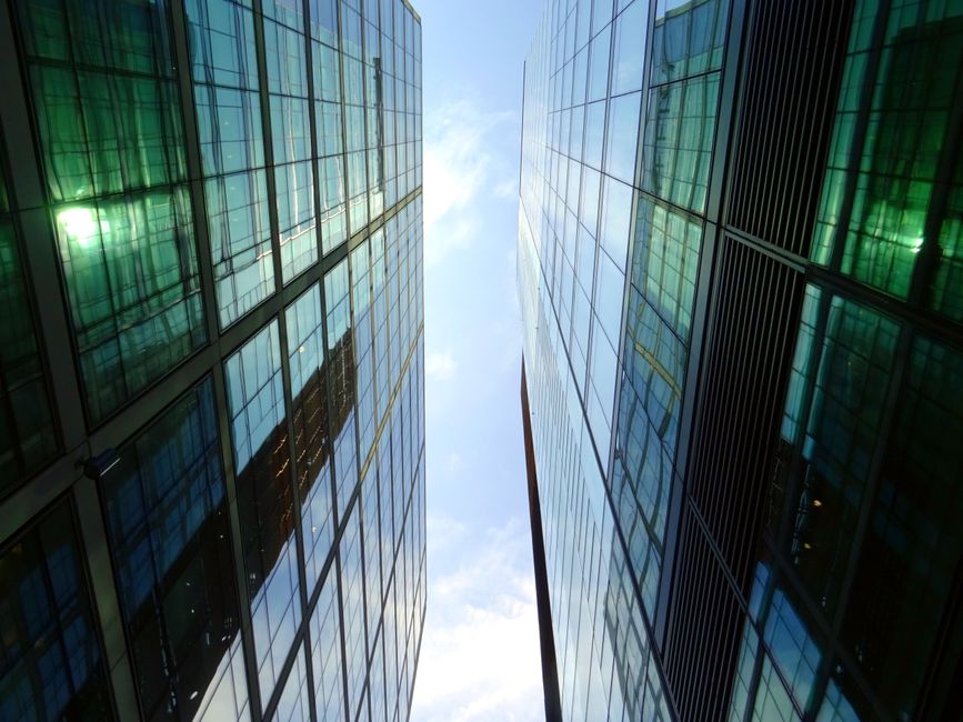 Low angle view of glass skyscrapers reflecting blue sky in a contemporary urban setting.