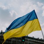 The Architecture of Sovereignty: 1272 Lessons for Strategy Waving Ukrainian flag against a cloudy sky and city skyline, symbolizing national pride.