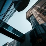 Dynamic low-angle shot of modern buildings with sky and dramatic shadows, emphasizing architecture.
