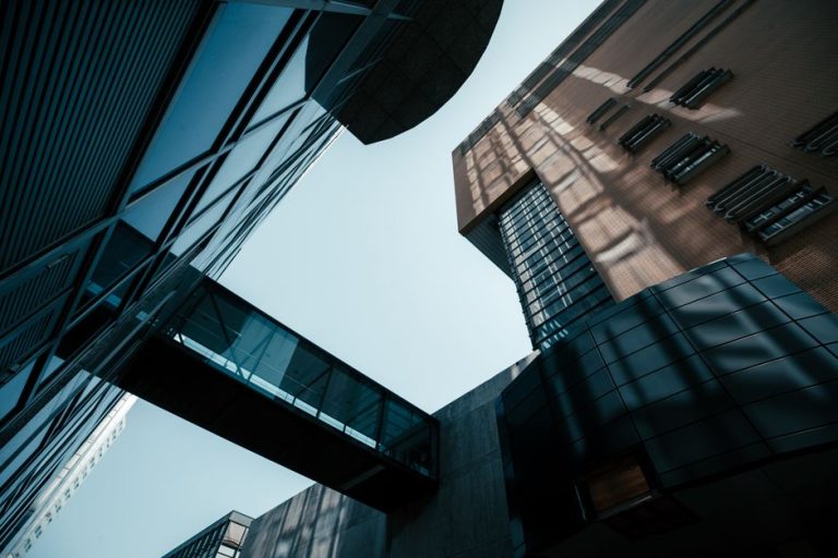 Dynamic low-angle shot of modern buildings with sky and dramatic shadows, emphasizing architecture.