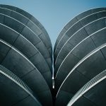 The Architecture of Trustless Coordination: DAO Governance Low-angle shot of a modern concrete structure with distinctive curved design against a clear sky.