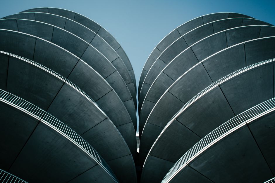Low-angle shot of a modern concrete structure with distinctive curved design against a clear sky.