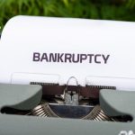 The Bio-Debt Crisis: Why Your Balance Sheet Isn't Prepared for Biological Depreciation Close-up of a typewriter with the word 'BANKRUPTCY' on paper, surrounded by greenery.