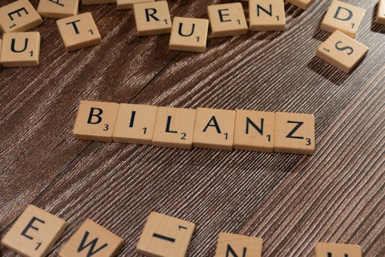Scrabble tiles spelling 'Bilanz' on a wooden surface, symbolic of financial balance.