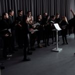 The Conductor’s Silence: Mastering the Strategic Pause in High-Stakes Leadership A choir practicing under a conductor's guidance in an indoor studio setting.