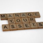 Wooden tiles spelling 'Manage Your Assets' offer conceptual business advice.