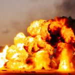 Powerful explosion with massive flames and smoke during daytime.