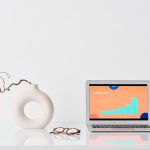 The Data Minimalist’s Advantage: Why Less Is Your Strongest Competitive Moat A minimalist workspace with a laptop, ceramic vase, and eyeglasses on a white desk.