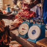 The Decoupling Paradox: Scaling Economic Growth Without Waste Fresh meat being weighed in a vibrant local market setting.