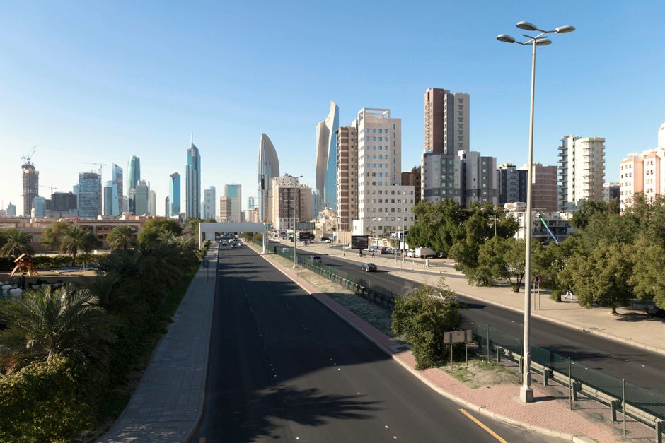 Panoramic view of Kuwait City skyline featuring modern skyscrapers and urban landscape under a clear sky.