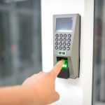 A person uses a fingerprint scanner for secure entry in a business setting.