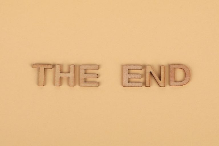 Wooden letters spelling 'The End' on a plain beige background, perfect for endings.