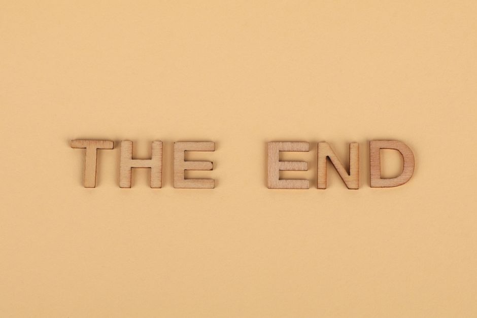 Wooden letters spelling 'The End' on a plain beige background, perfect for endings.