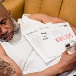 Sleeping man with financial documents, symbolizing stress and bankruptcy.