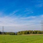 High voltage power lines stretch across a lush green field in Winterthur, Switzerland.