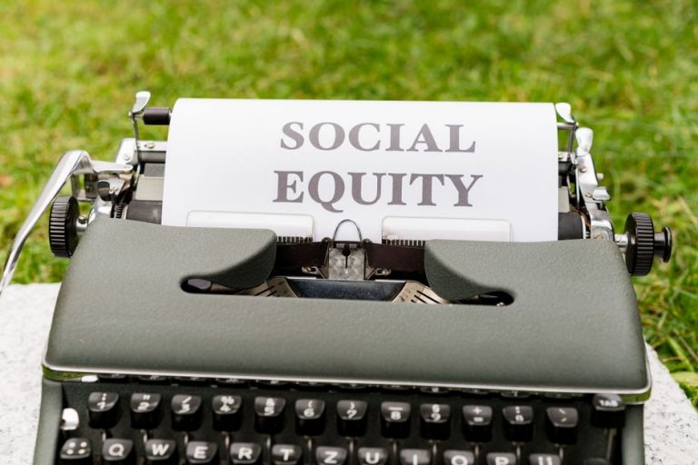 Close-up of a vintage typewriter with 'Social Equity' typed on paper outdoors.
