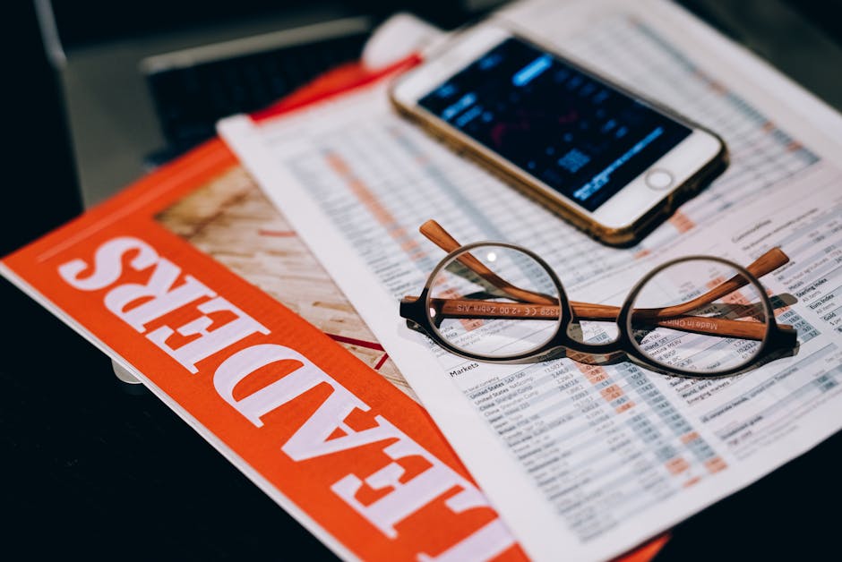 A close-up of business analytics tools including a smartphone, eyeglasses, and papers.