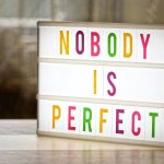 The Fallacy of 'Zero-Harm': Why Perfectionism is the Enemy of Clinical Safety Illuminated lightbox displaying the motivational slogan 'Nobody is Perfect'.