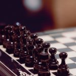 The Fermi Paradox: Strategic Lessons in High-Stakes Planning Close-up of black chess pieces aligned on a chessboard, ready for play.
