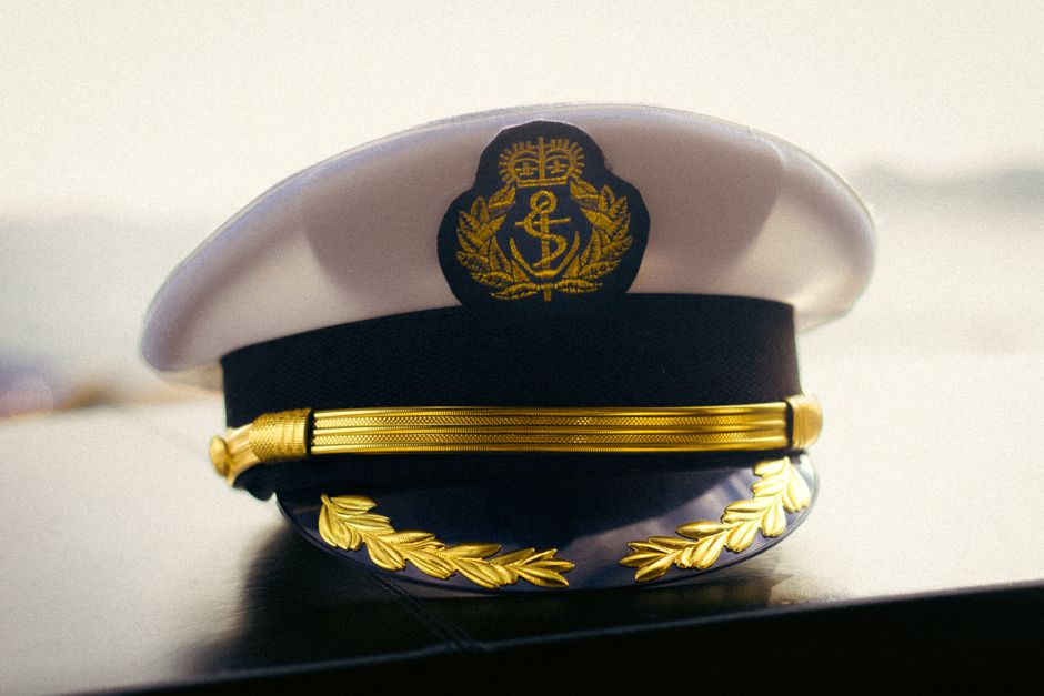 Close-up of a captain's hat displaying intricate gold embroidery, symbolizing authority.