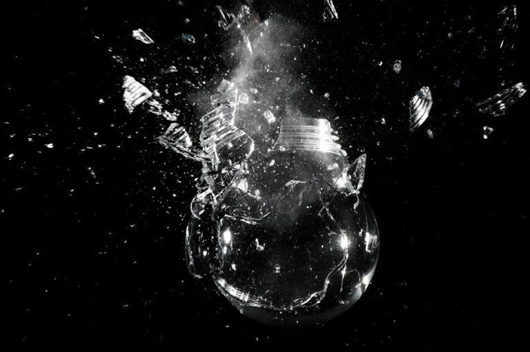 A dramatic image of a light bulb shattering into pieces against a dark background.