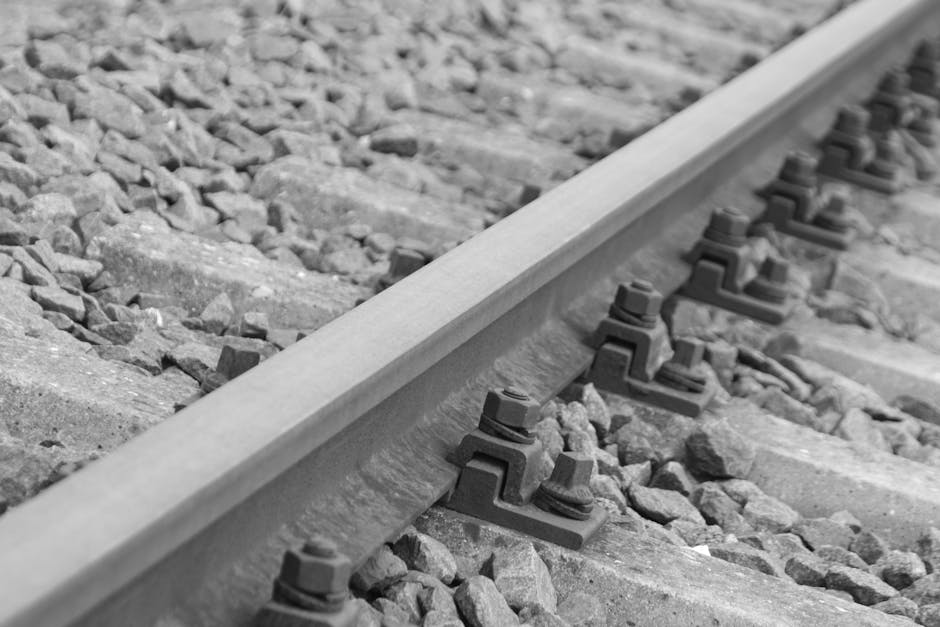 Artistic black and white photo of a railway track showing details of rails and gravel.