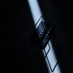 Newton's cradle in a dark room with striking light, showcasing physics concepts.
