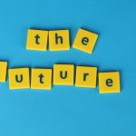 Yellow letter tiles spelling 'the future' on a blue surface, minimalist style.