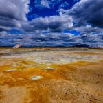 The Geothermal Renaissance: Scalable Baseload Power Strategy Vivid geothermal landscape with steam vents under a dramatic cloudy sky.