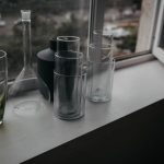 Group of glass vessels on a window sill with outdoor view.